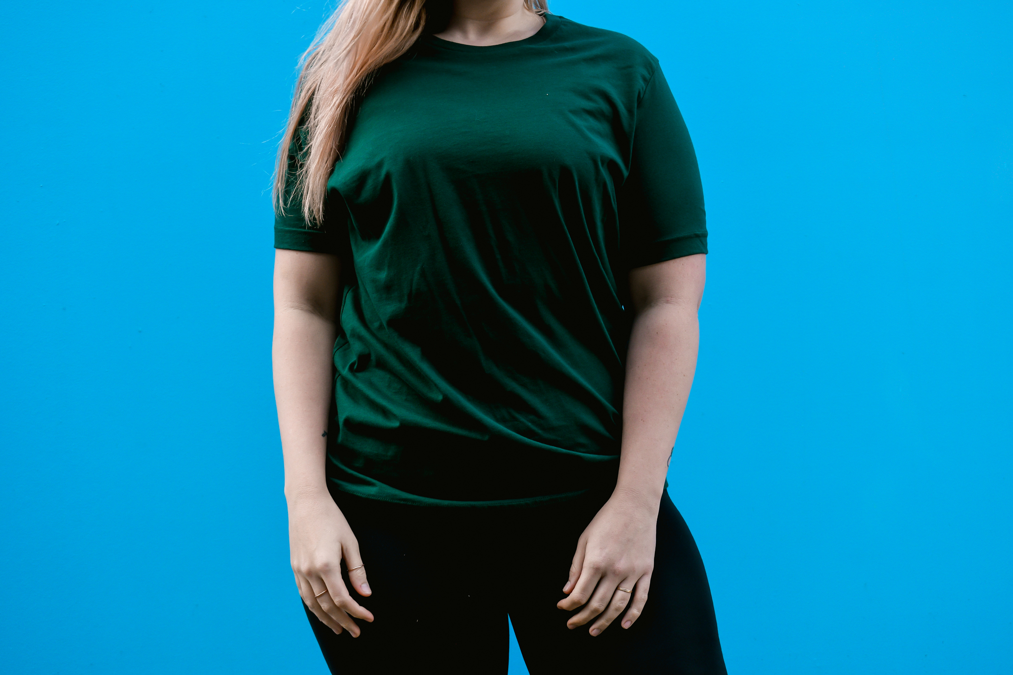 Focus shot of a women wearing the Canvas 3001 in Forrest Green, just the t-shirt on a blue background 